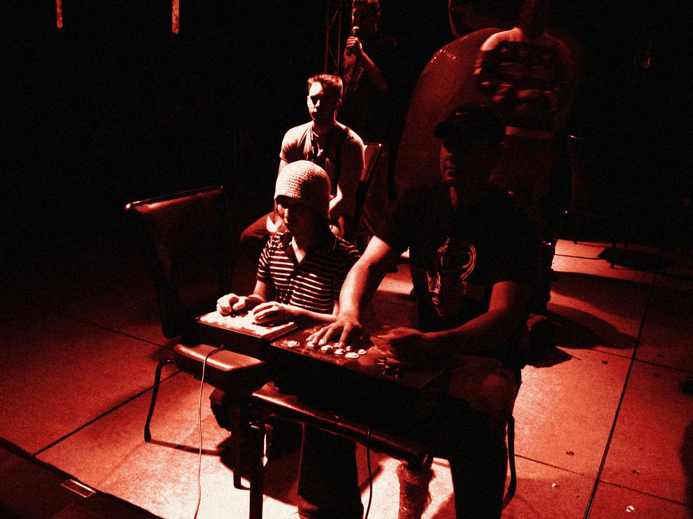 Alex at the controls on stage, players watching behind him